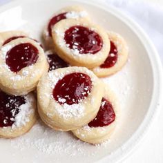 small pastries with powdered sugar and jelly on a white plate, ready to be eaten