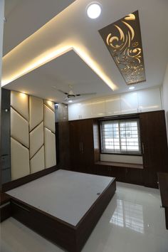 an empty room with a bed, cabinets and ceiling fan in the center is lit by recessed lights