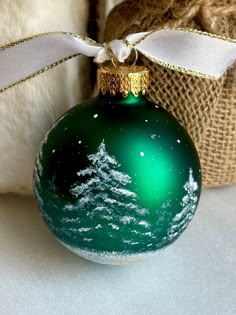 a green christmas ornament with a white ribbon