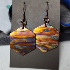 a pair of colorful earrings sitting on top of a piece of paper next to scissors