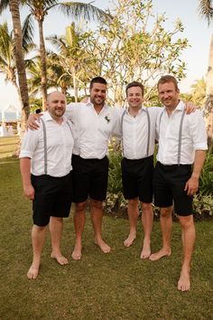 four men in white shirts and black shorts posing for the camera