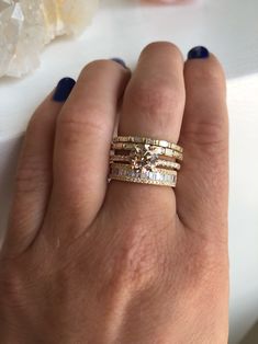 a woman's hand with three different rings on her left and the other one is wearing