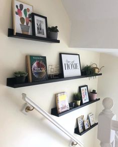 some shelves on the wall with pictures and books above them, along with other items