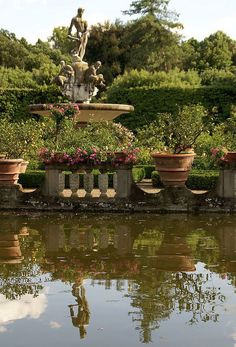 there are many potted plants in front of a fountain with a statue on it