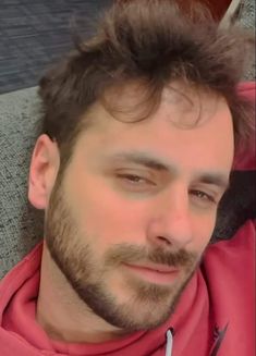 a close up of a person wearing a red jacket and looking at the camera with a serious look on his face