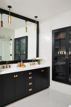 a black and white bathroom with gold accents on the sink, mirror, and cabinets