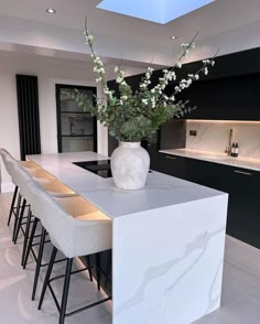 a vase with flowers sitting on top of a counter in a kitchen next to bar stools