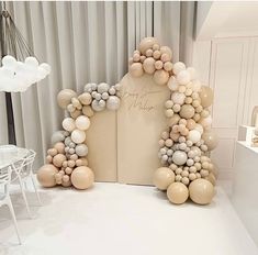 an arch made out of balloons is on display in a room with white walls and curtains