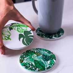 two plates with green leaves on them and a cup next to one that has a drink in it