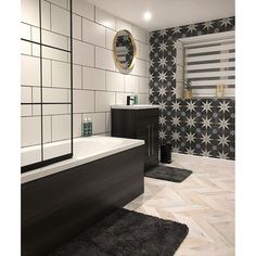 a bathroom with black and white tiles on the walls, flooring and bathtub