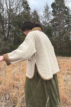 a woman standing in a field holding out her hand