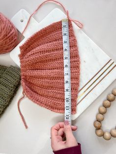 a person measuring the length of a knitted hat