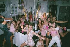 a group of young women standing around each other in front of a table with drinks and confetti