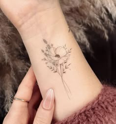 a woman's wrist with a flower tattoo on the left side of her arm