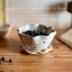 a bowl filled with blueberries sitting on top of a wooden table