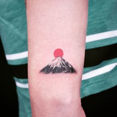 a small tattoo on the arm of a person with a red dot at the top