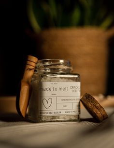 a jar with some kind of label on it next to a wooden spoon and potted plant