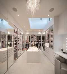 a room filled with lots of white furniture and chandelier hanging from the ceiling