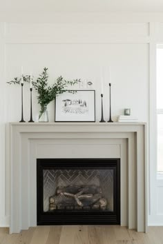 a white fireplace with candles and plants on top