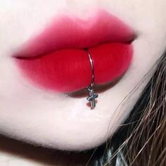 a close up of a person with red lipstick and cross on it's lip