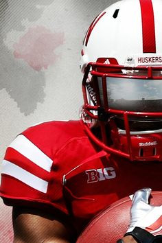 a close up of a football player wearing a red and white uniform with his helmet on