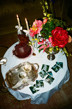 a table with flowers, candles and pictures on it