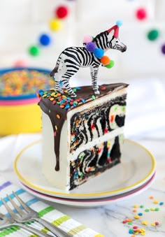 a zebra figurine on top of a piece of cake with chocolate frosting and sprinkles