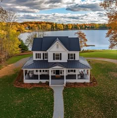 an aerial view of a large white house with a lake in the backgroud