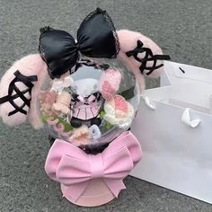 a pink and black stuffed animal in a clear ball with bows on it's head