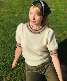 a woman sitting in the grass wearing a hat