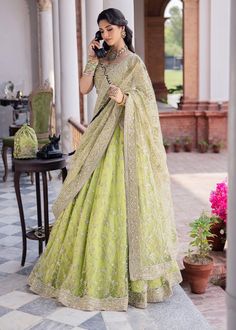 Pakistani Bridal Dress in Green Lehenga Choli Style is an embellished attire adorned with lavish designs and ornaments. Premium quality fabric and perfect stitching make this beautiful Lehenga Dress an epitome of beauty and your priority for the wedding. Lehenga Choli: The beautiful choli in alluring parrot green shade is fully adorned with hand-crafted details of sequins, pearls, stones, beads, zardosi, and embroidery. The lavish contrast of blue, pink, and goldwork make this choli a perfect choice to pair with Lehenga and wear on your wedding. Green Lehenga: The Bridal Lehenga has premium quality net fabric and it looks perfect when paired with the heavily embellished choli. The Lehenga has a huge flare and is adorned with beads, stones, threads, and embellished borders, giving a flawles