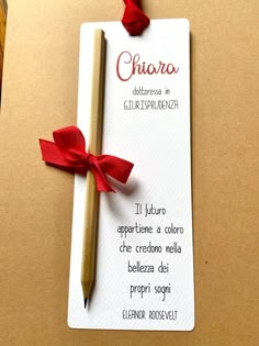 a note with a red ribbon and a pencil on it that is attached to a card