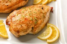 two pieces of chicken on a plate with lemons