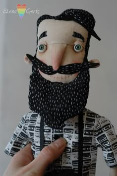 a close up of a person holding a doll with a beard and mustache on it's head