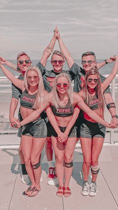 a group of young women standing next to each other on top of a roof near the ocean