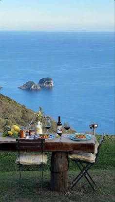 the table is set with food and wine overlooking the water's edge, along with an island in the distance