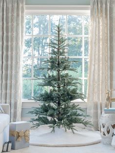 a small christmas tree sitting in front of a window