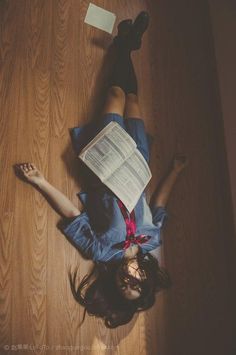 a woman laying on the floor reading a book