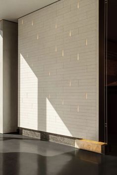 an empty room with white brick walls and concrete flooring in front of the window