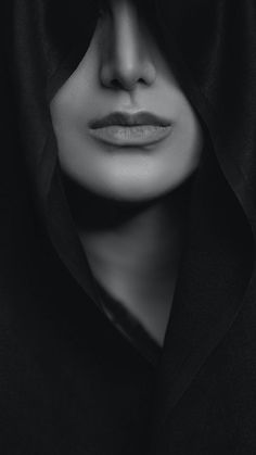 a woman wearing a black hoodie with her face covered by a veil and looking into the distance