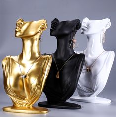 three mannequins with gold and silver jewelry on them, one in the shape of a woman's head