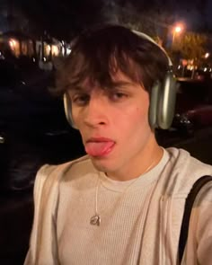 a young man wearing headphones making a funny face at the camera with his tongue sticking out