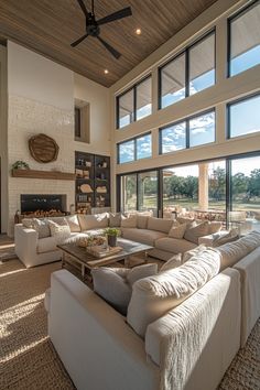 a large living room with lots of windows and couches in front of the fireplace