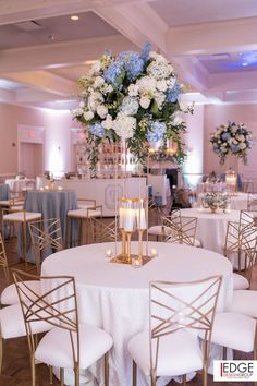 an elegant centerpiece with blue and white flowers is displayed in the middle of a banquet room