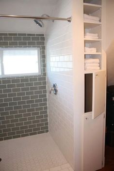 a bathroom with white tile and gray brick walls, along with a walk in shower