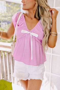 - We are totally crushing on this adorable top! - Unlined linen blend material - An elastic v-cut neckline and back - A removable accent bow that is pinned on - Short sleeves - A relaxed silhouette that ends in a straight hemline Chic Pink Top With Tie Back, Chic Pink Tie Back Top, Summer Bow V-neck Top, Spring V-neck Top With Bow, Spring V-neck Top With Bow Detail, Sleeveless Cotton Top With Bow Tie Back, Feminine Sleeveless Top With Bow Tie Back, V-neck Top With Bow For Spring, Pink Tie-back Top For Vacation