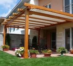 an outdoor patio with potted plants on the grass and a pergolated roof