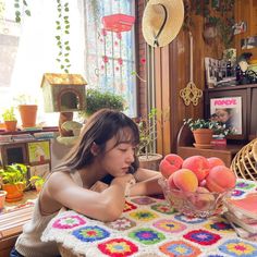 a woman sitting at a table with fruit in a bowl on top of the table