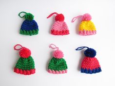 six crocheted hats are shown on a white surface, one is red, one is green and the other is blue