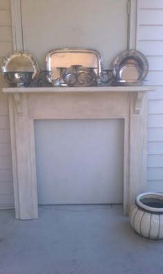 there is a fireplace with silver dishes on it